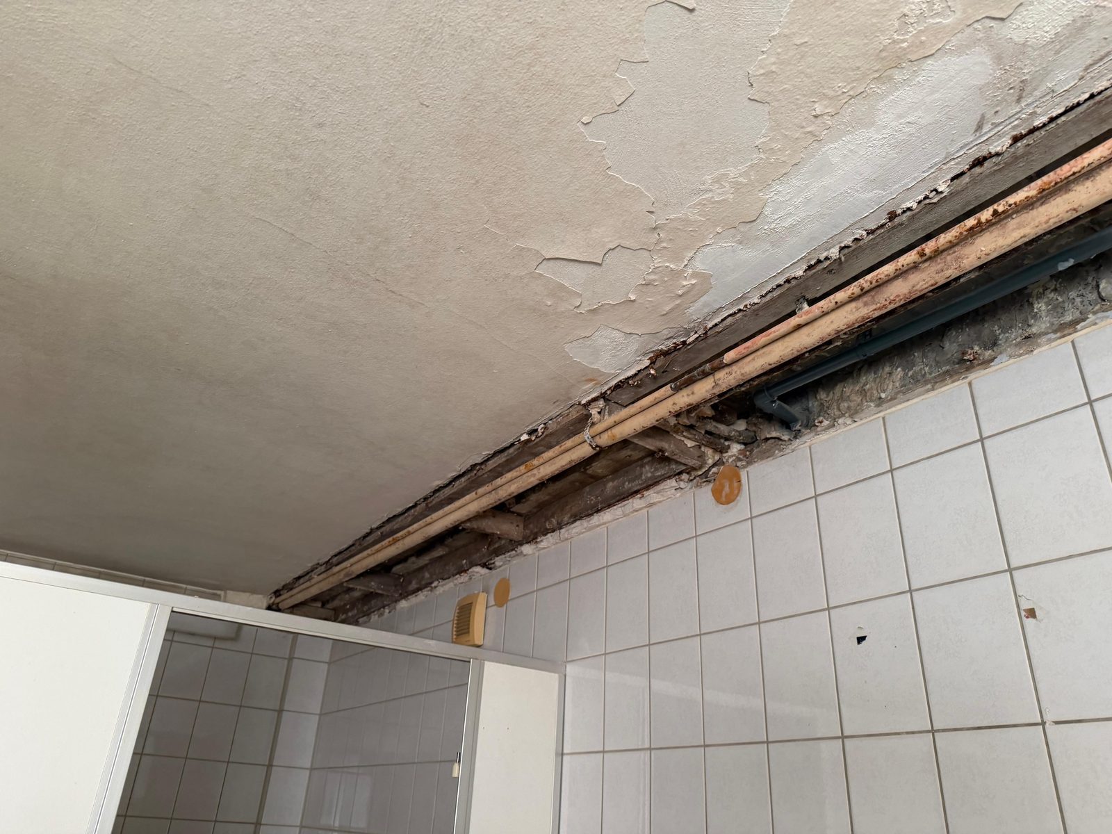 Zurückgebaute Bad-Decke mit freigelegten Leitungen während der Sanierung